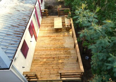 Vue sur une terrasse en bois rénovée avec le configurateur 3D de Glampinovateur, dans un camping des Landes, montrant l'intégration harmonieuse avec l'environnement naturel.