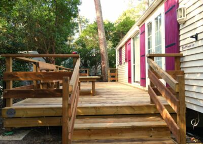 Terrasse en bois rénovée avec escalier et mobilier, posée sur plots en PVC, réalisée avec le configurateur 3D de Glampinovateur, dans un camping des Landes.