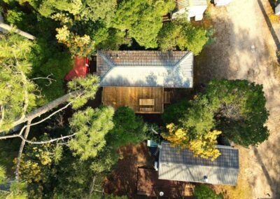 Vue aérienne d’une terrasse en bois conçue avec le configurateur 3D de Glampinovateur, installée dans un camping des Landes, entourée par les arbres.