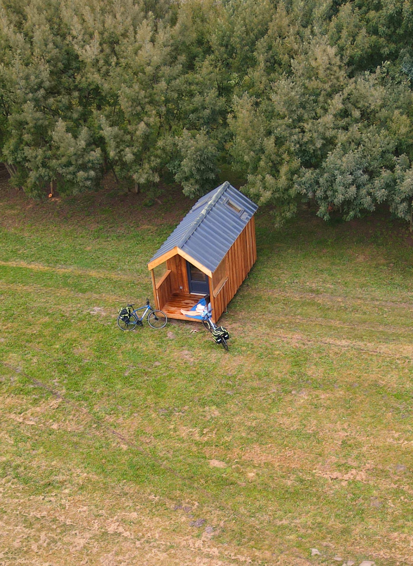 Hébergement insolite en bois pour camping et gîte – Le Rêveur Confort fabriqué en France Vue aérienne d’un hébergement insolite en bois avec terrasse, niché dans un environnement naturel, modèle "Le Rêveur Confort" conçu par GLAMPINOVATEUR pour campings et gîtes.