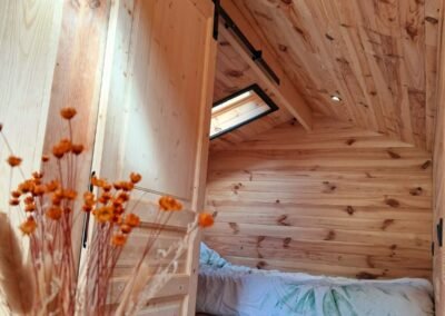 Intérieur d'un pod en bois pour camping – Hébergement insolite avec lit double et toilettes sèches, conçu par Glampinovateur.