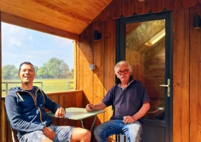 Le propriétaire du camping familial en Normandie pose sur la terrasse du Rêveur Confort, un hébergement insolite en bois conçu par Glampinovateur.