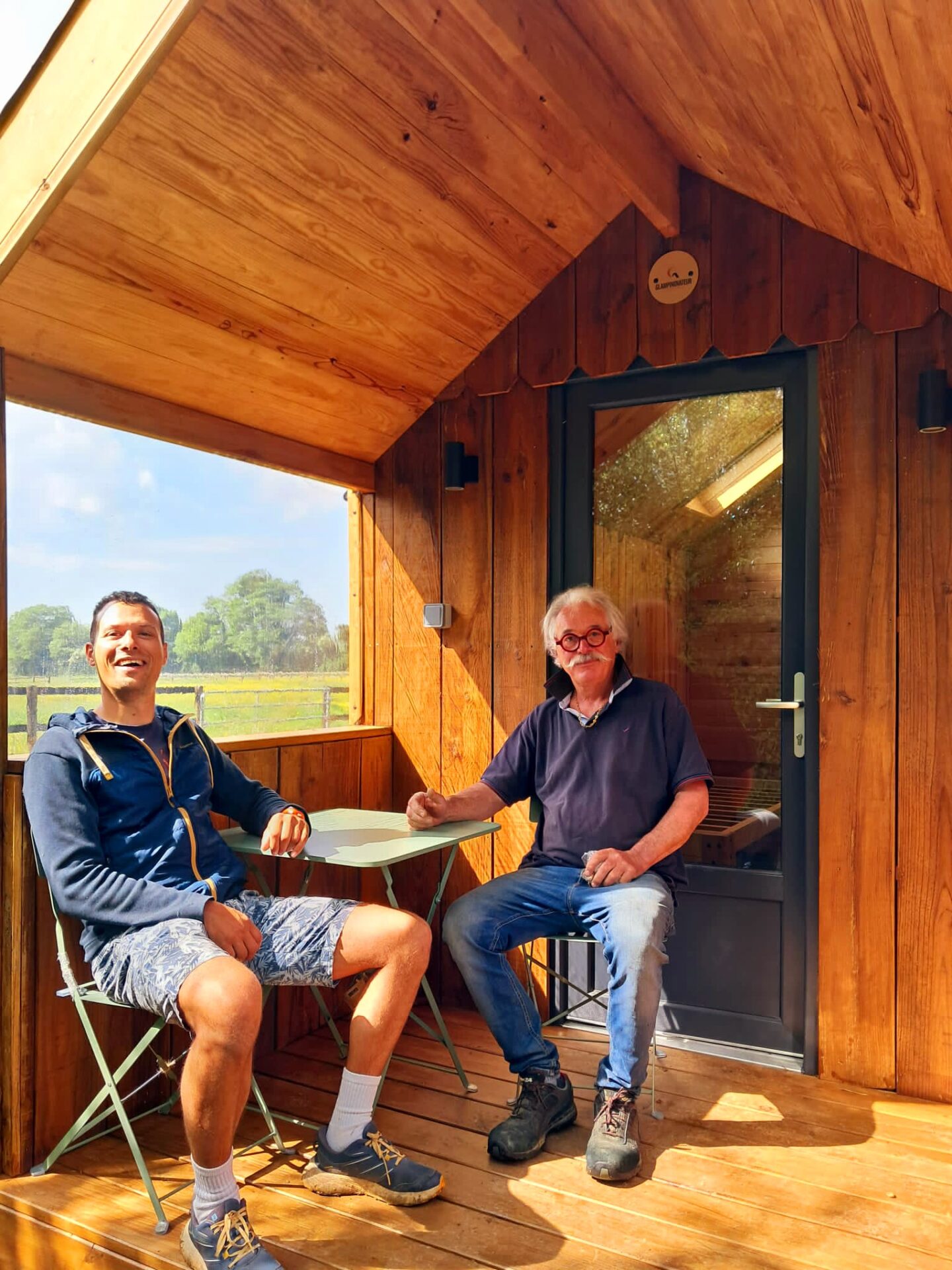 Terrasse du Rêveur Confort – hébergement insolite conçu par Glampinovateur avec le propriétaire du camping familial en Normandie Le propriétaire du camping familial en Normandie pose sur la terrasse du Rêveur Confort, un hébergement insolite en bois conçu par Glampinovateur.