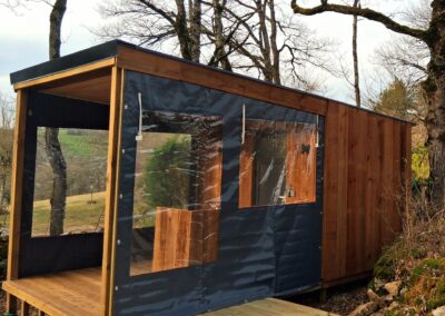 Sanitaire individuel innovant pour camping, avec terrasse et bâches latérales pour protection contre les intempéries – Modèle 'Campeur' de Glampiovateur, expert en hébergements insolites.