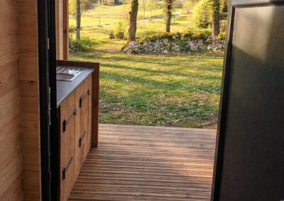 ntrée avec porte en PVC et terrasse avec belle vue pour le modèle Campeur, un sanitaire individuel de camping offrant confort et vue agréable.