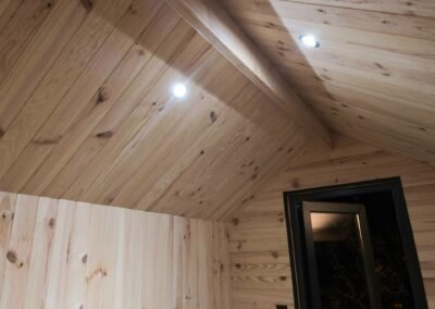 Intérieur de chalet en bois pour hébergement insolite à Saint-Malo, lambris naturel en pin des Landes, poutres apparentes et ambiance lodge glamping