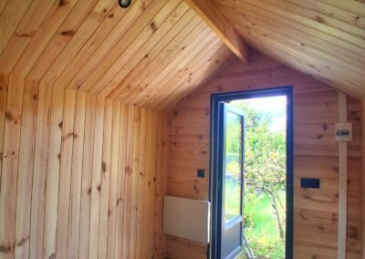 Intérieur de chalet bois pour hébergement insolite à Saint-Malo, lodge glamping avec porte vitrée, chauffage et espace chaleureux modèle Rêveur